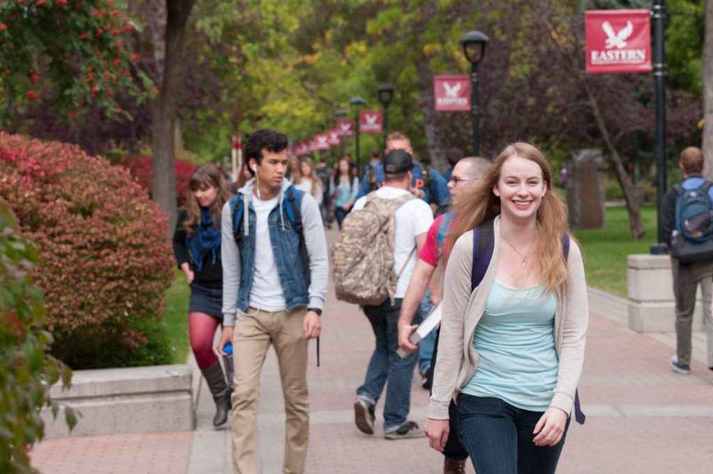Students walking on path, one smiling at the camera